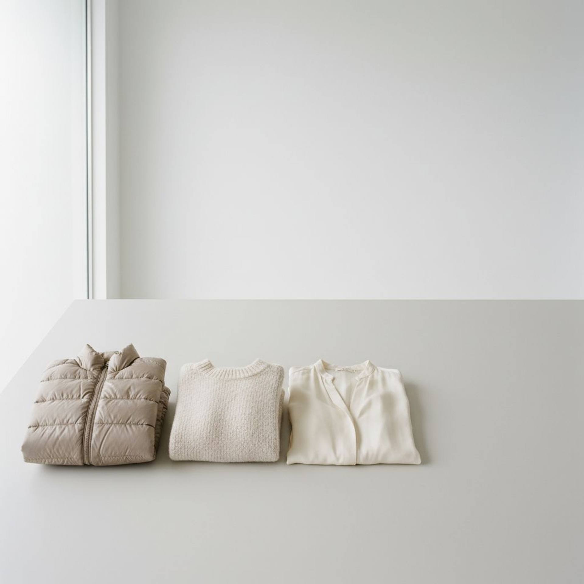 Down jacket, wool sweater, and silk blouse arranged side by side, prepared for assessment of whether refreshing is enough instead of washing