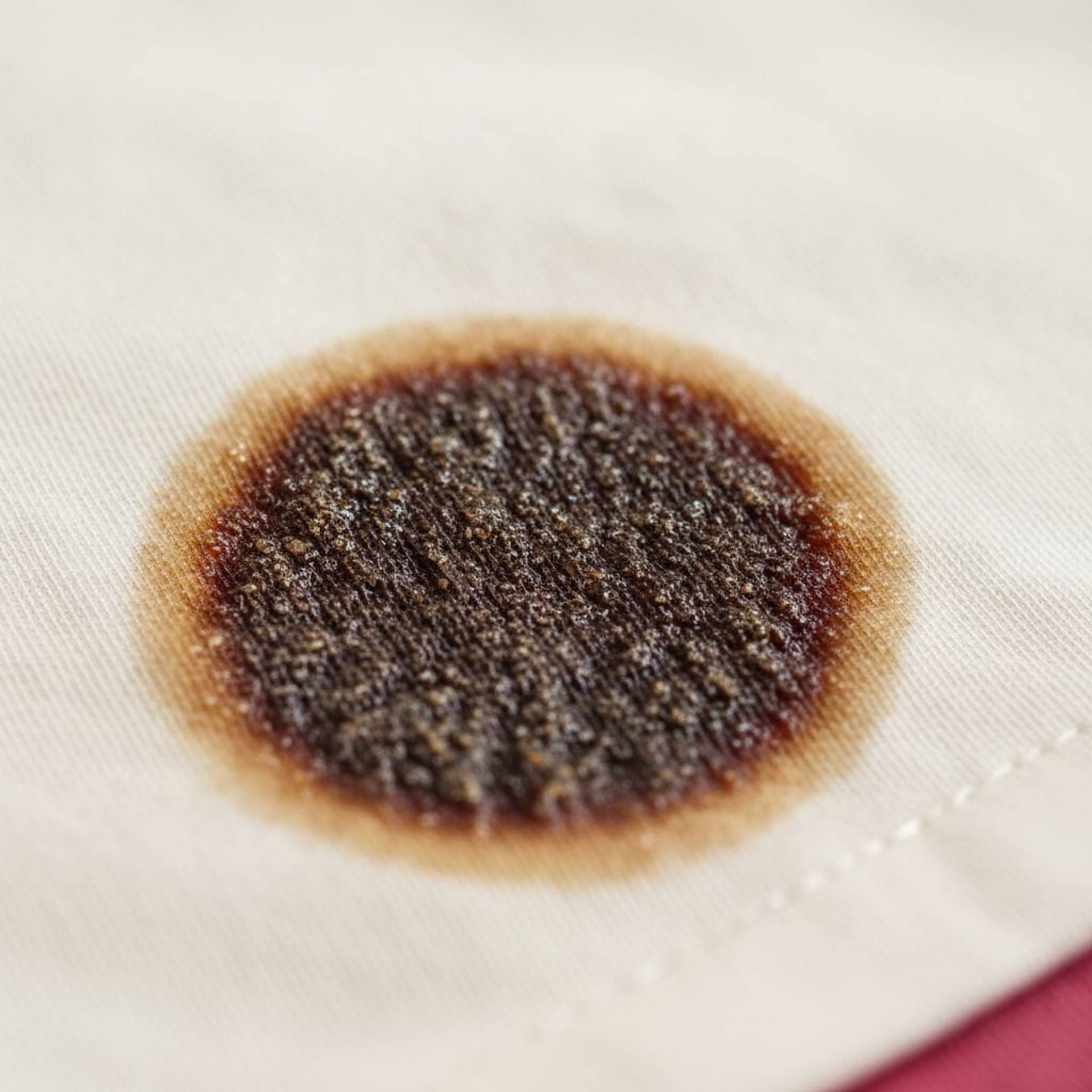 plama po coca-coli na jasnej bawełnianej koszuli z widoczną lepką powłoką